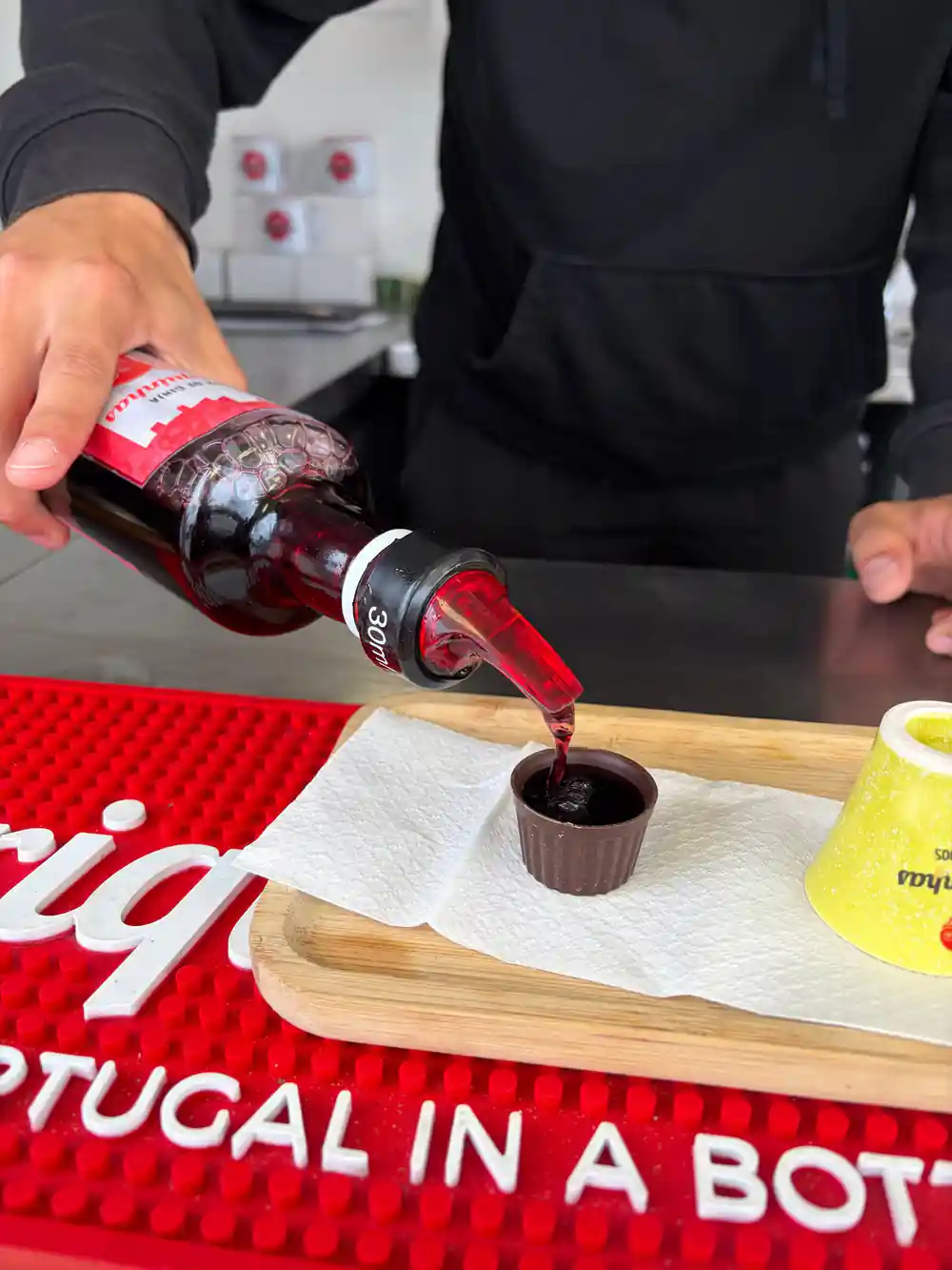 Cherry liqueur poured into a small chocolate cup on a wooden board