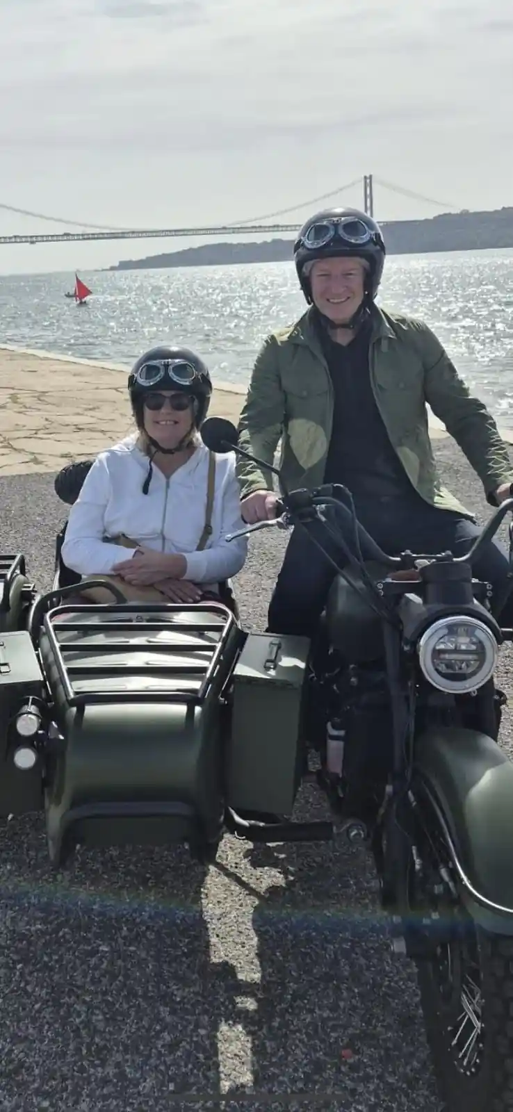 A couple standing behind a dark green sidecar