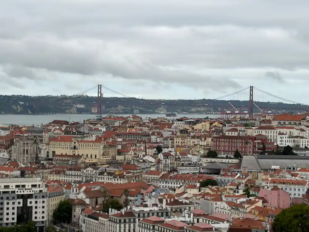 Lisbon rooftops falling away with the suspension bridge on the horizon