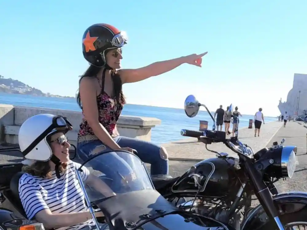 A rider in helmet and goggles pointing out across the water from the chair