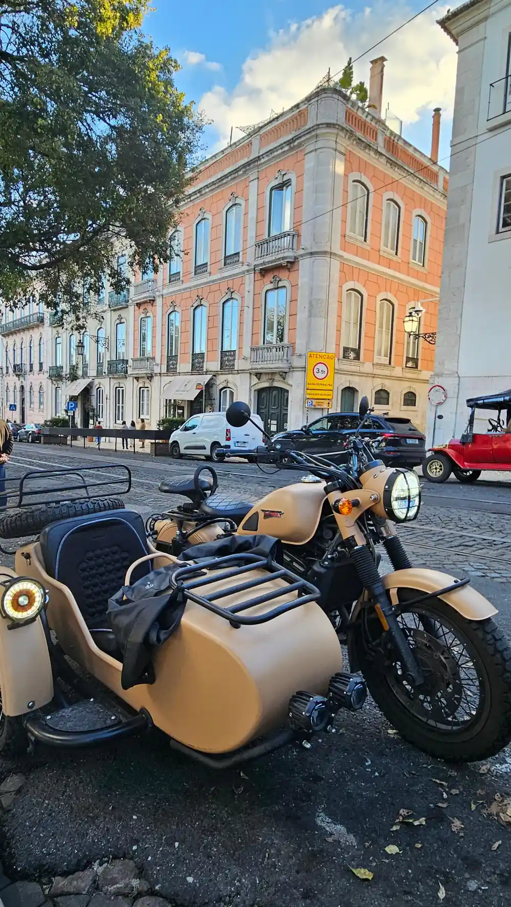 A tan sidecar outfit parked on a street of pastel buildings
