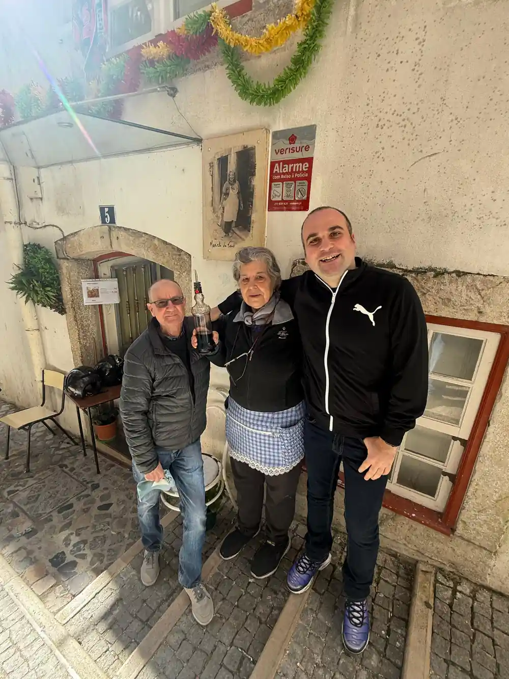 Three people with drinks outside a small tiled tavern
