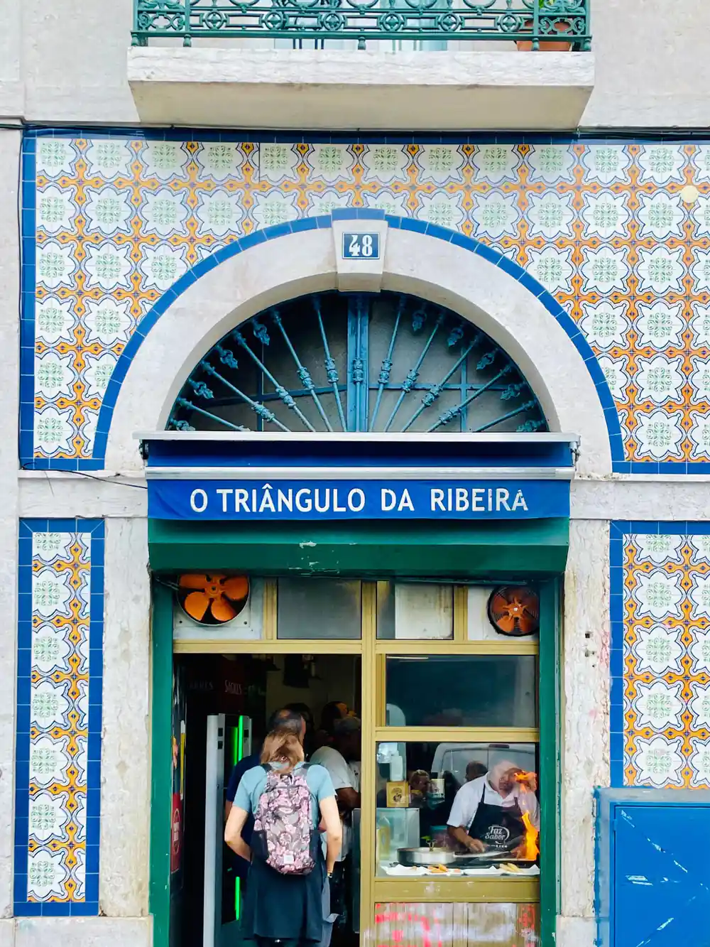 A tiled shopfront under an arched blue and orange azulejo surround