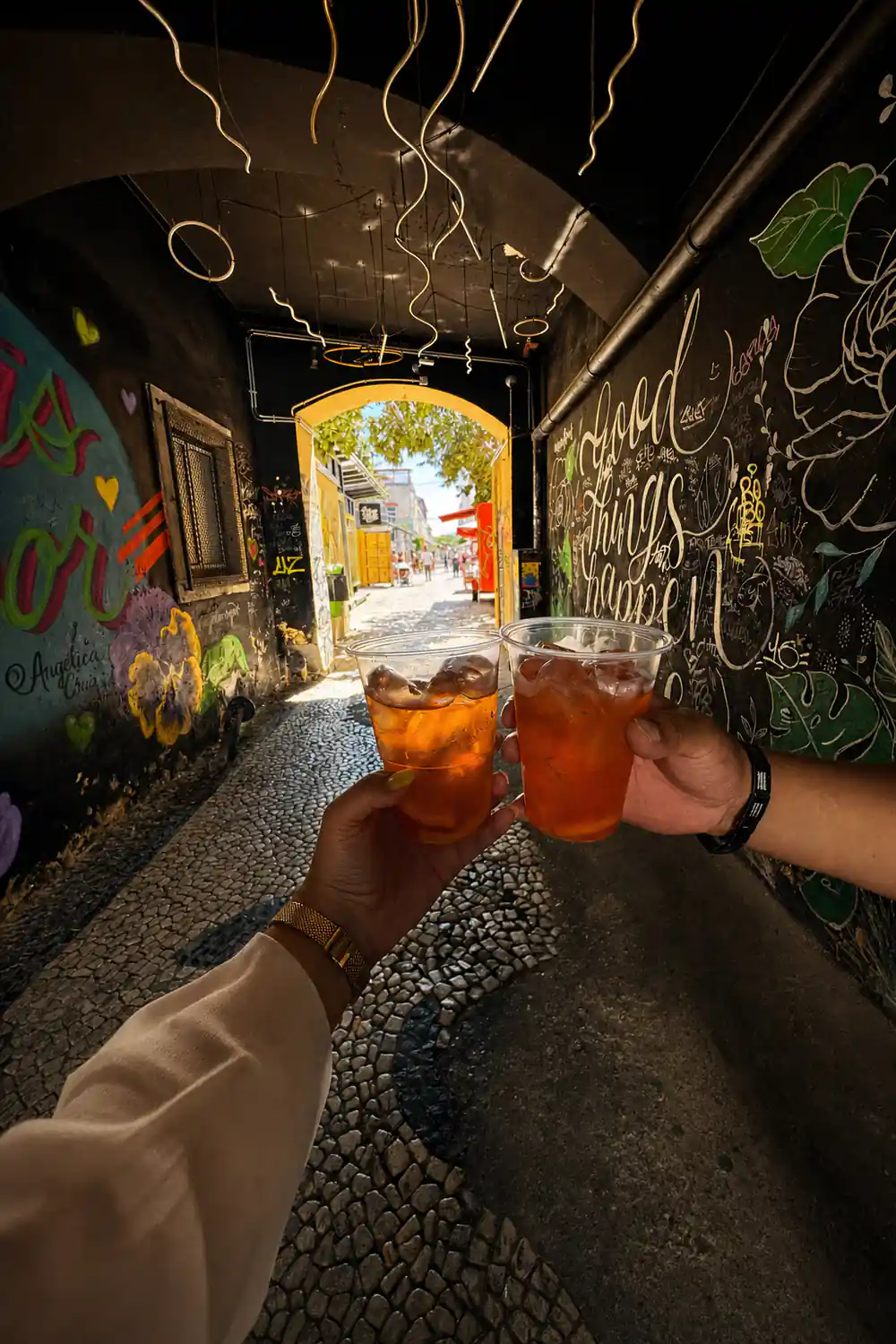 Two glasses raised together in a graffiti painted archway