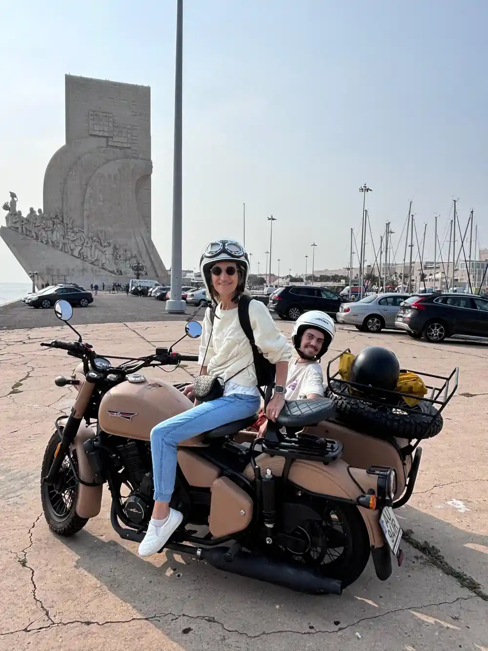 Two riders on a tan sidecar by the marina below the discoveries monument